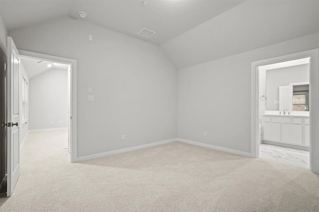 interior space featuring lofted ceiling, connected bathroom, and light carpet