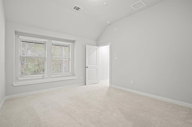 spare room featuring vaulted ceiling and light colored carpet