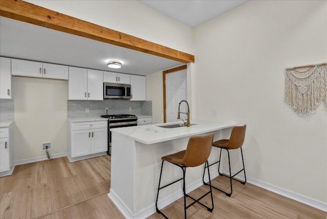 kitchen featuring decorative backsplash, light hardwood / wood-style flooring, stainless steel appliances, sink, and white cabinetry