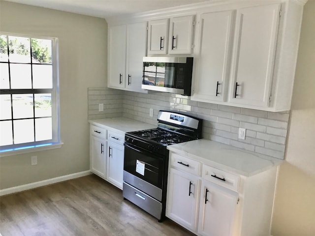 kitchen with light stone countertops, white cabinetry, stainless steel appliances, and backsplash