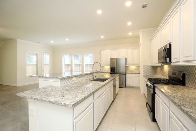 kitchen with sink, a kitchen island with sink, stainless steel appliances, and white cabinetry