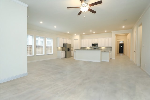 kitchen with tasteful backsplash, ornamental molding, an island with sink, and white cabinets