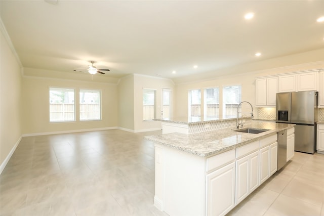 kitchen with white cabinets, tasteful backsplash, appliances with stainless steel finishes, a kitchen island with sink, and sink