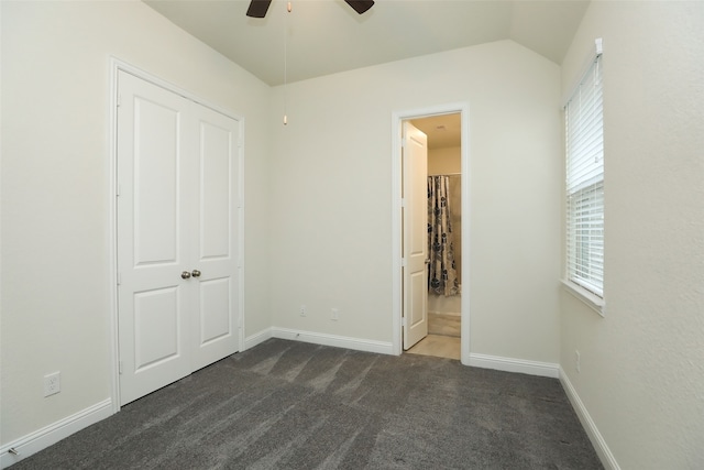 unfurnished bedroom with a closet, ceiling fan, vaulted ceiling, and dark colored carpet