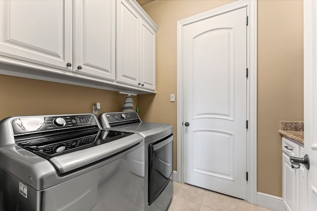 laundry room with light tile patterned floors, cabinets, and washer and clothes dryer