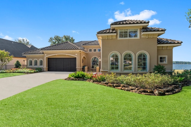 mediterranean / spanish home featuring a garage and a front lawn