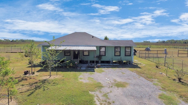 view of front of home featuring a rural view, driveway, a front lawn, and fence