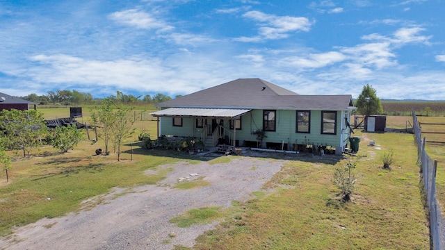 view of front of property featuring driveway, a rural view, and fence