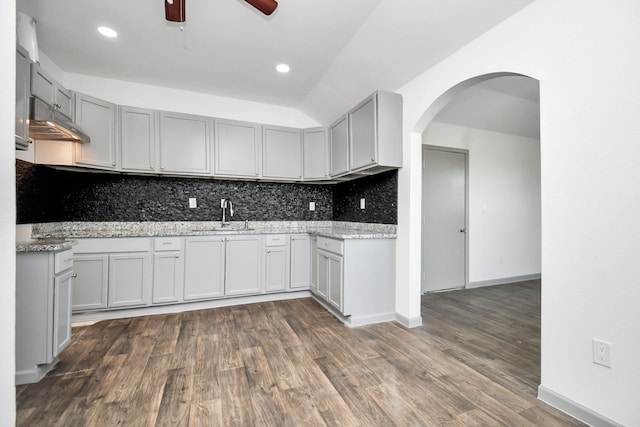 kitchen with light stone countertops, backsplash, gray cabinetry, ceiling fan, and sink