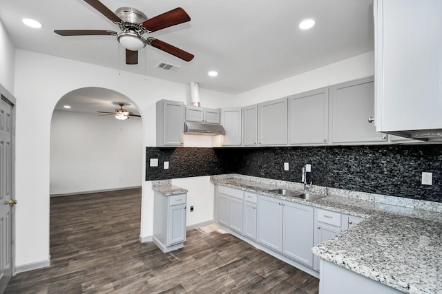 kitchen featuring light stone countertops, decorative backsplash, dark hardwood / wood-style floors, and sink