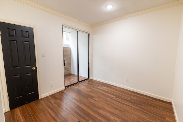 unfurnished bedroom featuring dark wood-type flooring, crown molding, and a closet