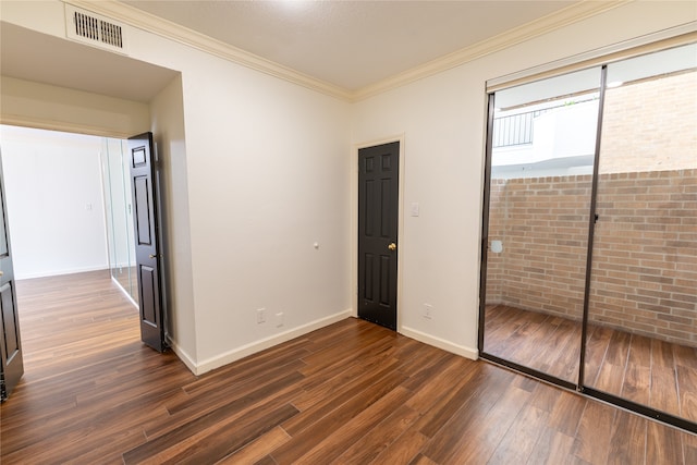 unfurnished bedroom featuring dark hardwood / wood-style floors, ornamental molding, brick wall, and a closet