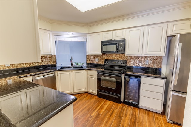 kitchen featuring beverage cooler, sink, black appliances, light hardwood / wood-style flooring, and white cabinetry