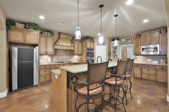 kitchen with hanging light fixtures, premium range hood, concrete floors, a kitchen island with sink, and stainless steel appliances