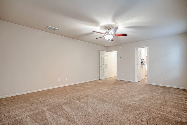 empty room with a textured ceiling, light colored carpet, and ceiling fan