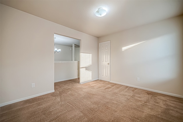 carpeted empty room featuring a chandelier