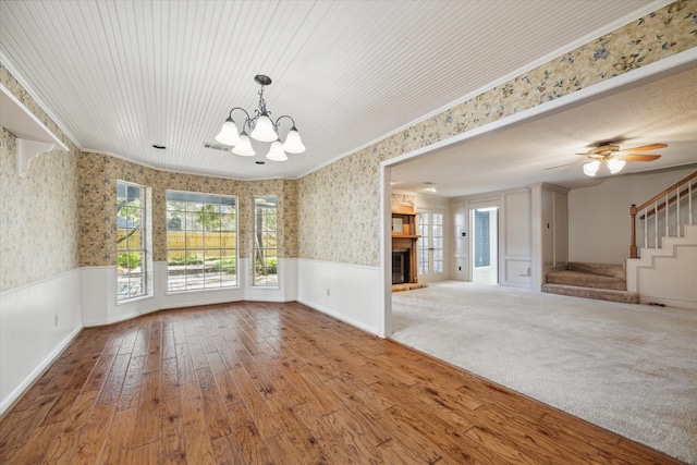 unfurnished dining area with ornamental molding, hardwood / wood-style flooring, and ceiling fan with notable chandelier