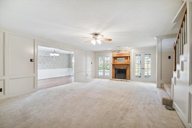 unfurnished living room featuring light carpet, french doors, a textured ceiling, and ceiling fan with notable chandelier