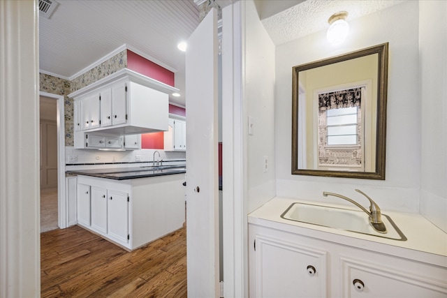 kitchen featuring hardwood / wood-style floors, sink, white cabinetry, and tasteful backsplash