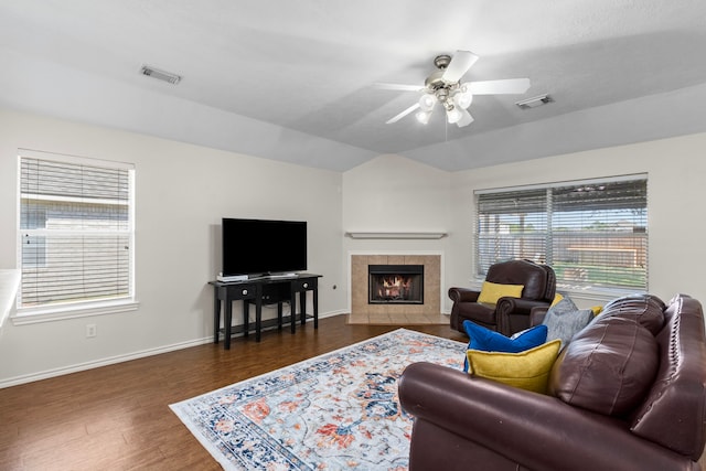 living room featuring dark wood-type flooring, a tiled fireplace, and ceiling fan