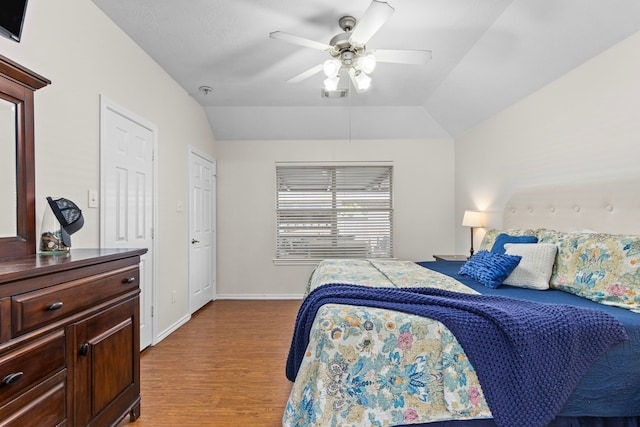 bedroom with light hardwood / wood-style flooring, vaulted ceiling, and ceiling fan