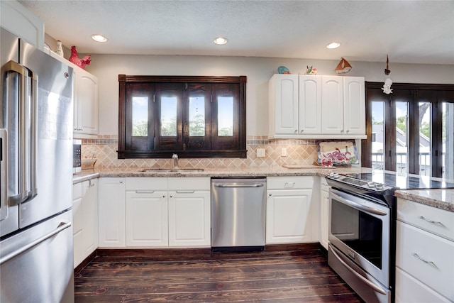 kitchen featuring sink, decorative backsplash, appliances with stainless steel finishes, light stone counters, and white cabinetry