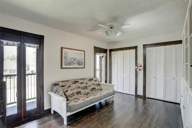 living area with ceiling fan, dark wood-type flooring, and a textured ceiling