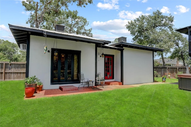 rear view of property featuring a lawn, a patio area, and french doors