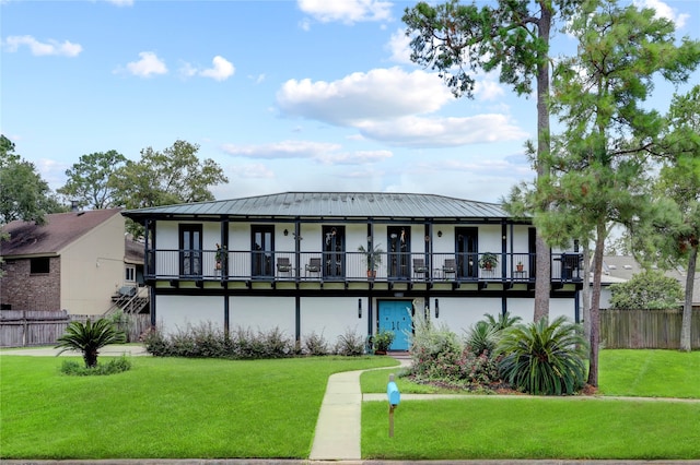 back of property with a yard and a balcony