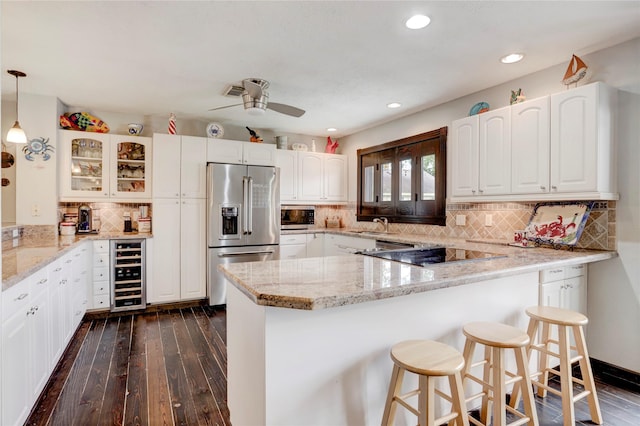 kitchen featuring appliances with stainless steel finishes, decorative light fixtures, white cabinetry, kitchen peninsula, and beverage cooler