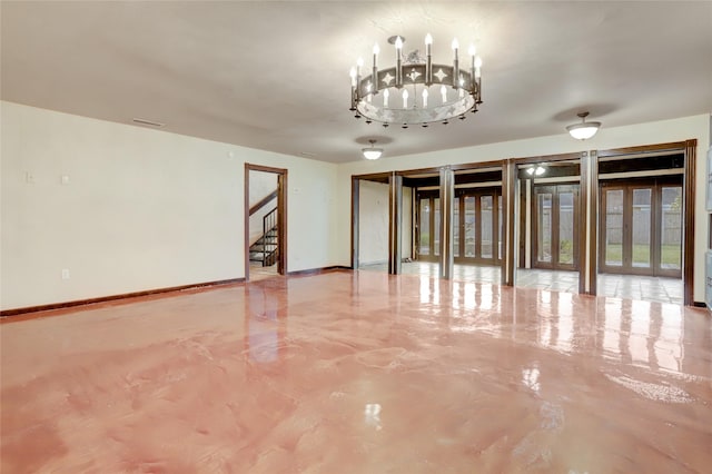 spare room featuring a chandelier and concrete flooring