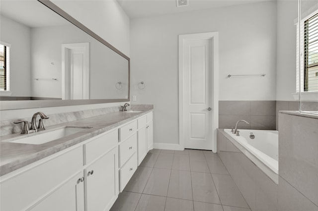 bathroom with vanity, a relaxing tiled tub, and tile patterned flooring