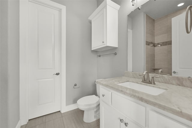 bathroom with vanity, tiled shower, toilet, and tile patterned floors