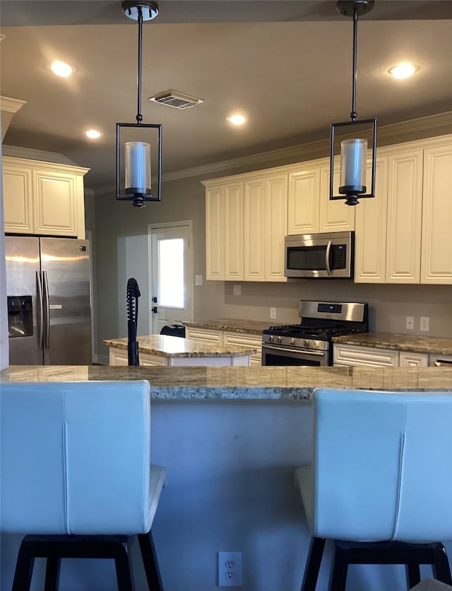 kitchen with a kitchen breakfast bar, appliances with stainless steel finishes, light stone counters, and pendant lighting