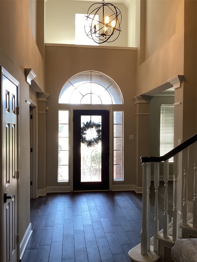 entrance foyer featuring a towering ceiling, an inviting chandelier, and ornate columns