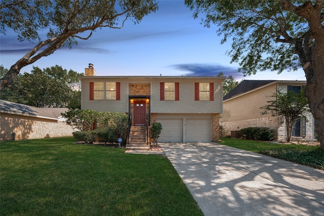 raised ranch featuring a garage and a lawn