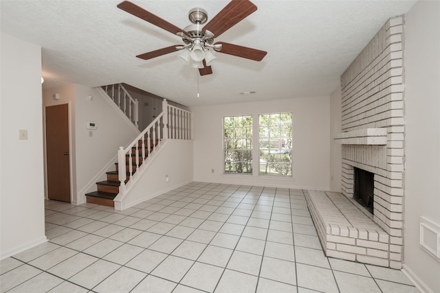 unfurnished living room featuring a textured ceiling, light tile patterned flooring, a fireplace, and ceiling fan