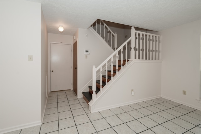 staircase featuring tile patterned floors and a textured ceiling