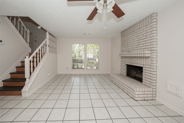 unfurnished living room featuring a textured ceiling, ceiling fan, light tile patterned floors, and a brick fireplace