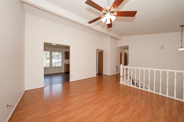 unfurnished room with a textured ceiling, hardwood / wood-style flooring, vaulted ceiling, and ceiling fan