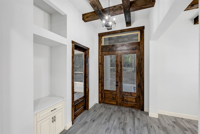 entrance foyer with french doors, a notable chandelier, beamed ceiling, and light hardwood / wood-style flooring