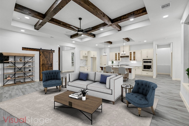 living room with sink, a barn door, coffered ceiling, beam ceiling, and light hardwood / wood-style flooring