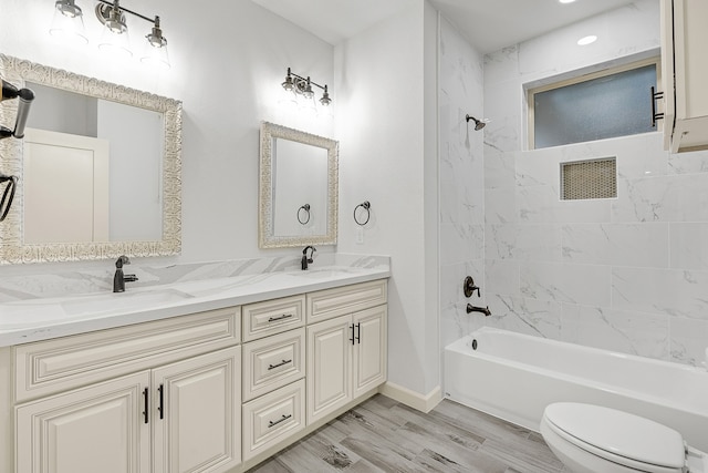 full bathroom featuring toilet, hardwood / wood-style floors, tiled shower / bath combo, and vanity