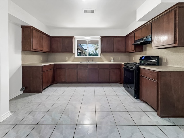 kitchen with black gas range, sink, dark brown cabinets, and light tile patterned floors