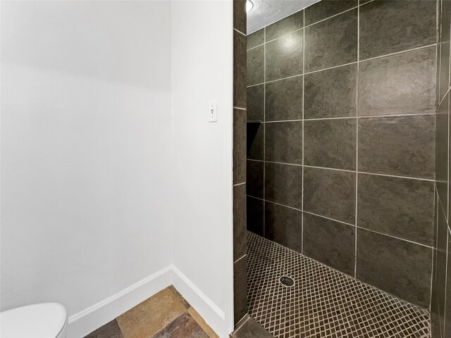 bathroom with toilet and tiled shower