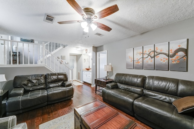 living room featuring a textured ceiling, ceiling fan, and dark hardwood / wood-style flooring