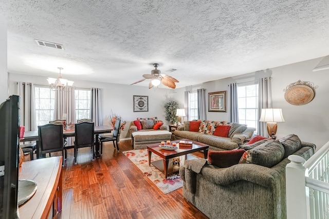 living room with dark wood-type flooring, a textured ceiling, and ceiling fan with notable chandelier