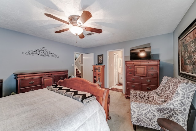 carpeted bedroom featuring a textured ceiling, ensuite bathroom, and ceiling fan