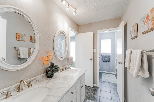 bathroom with vanity, toilet, tile patterned floors, and a textured ceiling