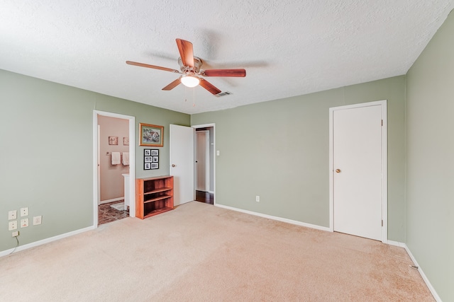 unfurnished bedroom with a textured ceiling, light colored carpet, and ceiling fan